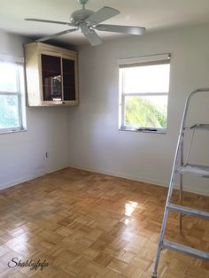 an empty room with hard wood floors and a ladder in front of the window that is open