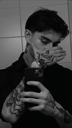 a man with tattoos taking a selfie in front of a mirror while holding his phone up to his face