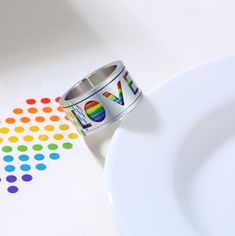 a ring with the word love on it sits next to a plate and colorful dots