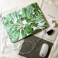 a computer mouse, book and headphones on a bed with a palm leaf print cover