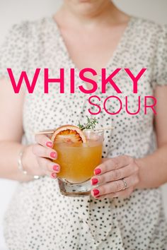 a woman holding a drink in her hands with the words whisky sour on it's side