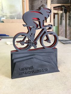 a metal sculpture of a man riding a bike on top of a black base with red lettering