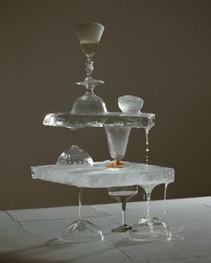 an ice sculpture with two glasses on top and one glass in the middle, sitting on a table