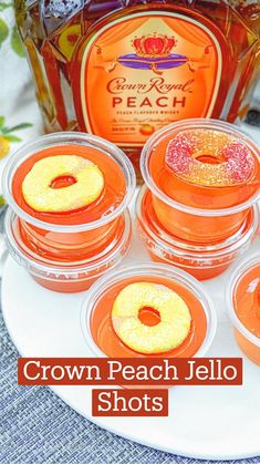 four orange jello shots sitting on top of a white plate next to a bottle