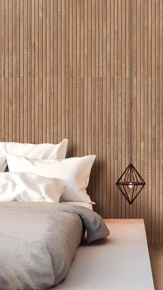 a bed with white sheets and pillows in front of a wall made of wood slats