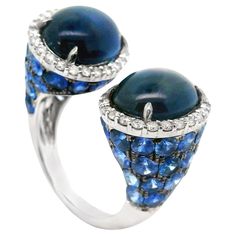 A unique and stylish ring in an open modern style. It features two large cabochon sapphires along with round blue sapphires weighing a total of 17.34 carats. It is accented by 0.72 carats of round brilliant-cut diamonds which add brilliance and sparkle to the piece. Made in 18k white gold and ready to be worn. Ring Size 6.50 Weight: 11.6 grams Stylish Rings, Blue Sapphire Diamond, White Gold Diamond Rings, Sapphire Diamond Ring, Gold Band Ring, Modern Ring, White Gold Band, Sapphire Stone, Gold Diamond Rings