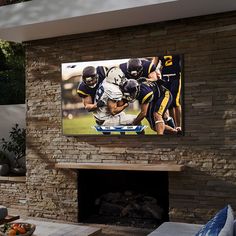 a large television mounted to the side of a brick wall next to a fire place