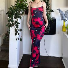 a woman standing in front of a potted plant and wearing a dress with flowers on it