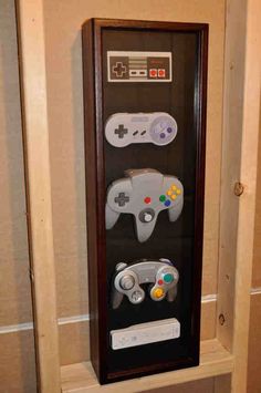 a display case with two video game controllers in front of it on the wall next to a toilet