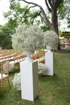 an outdoor ceremony set up with chairs and vases filled with baby's breath flowers