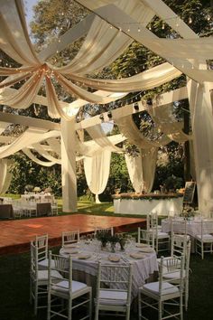 an outdoor wedding setup with white draping and tables set up for the guests