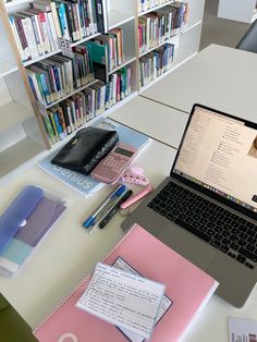 an open laptop computer sitting on top of a desk next to a pile of books