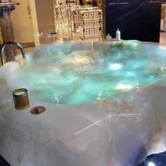 a large bath tub sitting on top of a black floor next to a display case