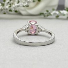 This beautiful ring is made from genuine 925 sterling silver with rhodium plating. Ring details- -The Main stone is an oval cut 8mm by 6mm Pink Simulated Diamond -Side stones are 1.5 Round simulated diamonds -Ring is casted in solid 925 sterling silver with rhodium plating (yellow gold and rose gold plated also available, please check the drop down menu for more options) -The Total face height of the ring measures 8mms and the band width measures 2mms -Each ring is handmade and made to order, so Silver Oval Birthstone Ring With Polished Finish, Silver Oval Promise Ring, Oval Hallmarked Promise Birthstone Ring, Silver Oval Halo Design Birthstone Ring, Silver Oval Birthstone Ring With Halo Design, Silver Oval Halo Birthstone Ring, Silver Oval Birthstone Ring With Center Stone, Sterling Silver Oval Birthstone Promise Ring, Silver Oval Birthstone Ring With Accent Stones