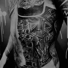 black and white photograph of a man's back with tattoos on his body, in front of dripping paint