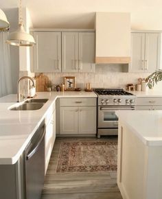 a kitchen with white cabinets and an area rug in front of the stove top oven