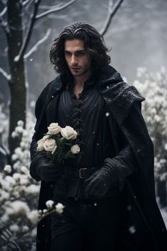 a man dressed in black holding flowers and looking at the camera with snow falling all around him