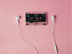 an old cassette player with ear buds plugged into it on a pink striped surface