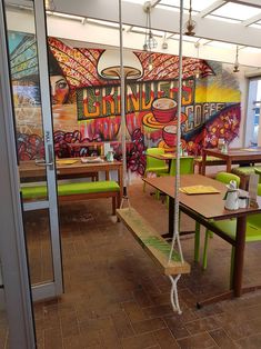 the inside of a restaurant with tables and green chairs in front of a mural on the wall