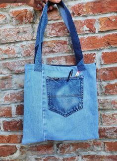 a person holding onto a blue jean bag with one pocket open and the other closed