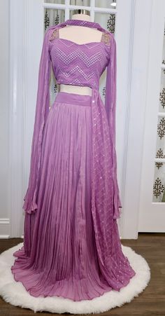 Beautiful Lavendar Crop top/Lehanga set with attached Trail on one side of the Blouse. The dress has elegant Zig zag pattern lucknawi work on Top and zardosi work on the shoulder. Sleeves are also provided. Comes with Butterfly style Dupatta with sequin work on it. Color: Lavender Size: XL 42 plus 2 inchesFabric: GeorgetteLehanga Waist: 39 inchesLehanga Length: 40 and 1/2 Inches Embellishments: Lucknawi work with sequin, mirror and zardosi work on top. Note: We accommodate on size adjustments wh Purple Georgette Palazzo Set With Traditional Drape, Traditional Drape Purple Georgette Palazzo Set, Navratri Purple Palazzo Set With Cutdana, Diwali Purple Palazzo Set With Traditional Drape, Traditional Sets With Dupatta And Side Open, Purple Palazzo Set With Pallu For Navratri, Traditional Side Open Sets With Dupatta, Purple Pre-draped Saree With Mirror Work For Navratri, Navratri Purple Pre-draped Saree With Mirror Work