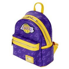 Express your Lakers pride with the NBA Los Angeles Lakers Logo Mini Backpack. The bag’s design pays homage to the iconic team, featuring the embroidered Los Angeles Lakers logo with the fast-moving golden basketball, prominently displayed over the front zip compartment. Both the front and back surfaces boast a debossed motif of the signature “L” and basketball, with dynamic streaking lines set against a purple background. Gold trim, mirroring the team's uniform color, adds a striking contrast to Sporty Logo Bags For Streetwear, Sporty Bags With Logo Patch For Streetwear, Sporty Travel Bag With Embroidered Logo, Sporty Standard Backpack For College, Sporty Backpack With Logo Patch, Sporty Leather Backpack, Sporty Standard Backpack With Logo Patch, Back To School College Bags With Zipper Closure, College Bags With Zipper Closure For Back To School