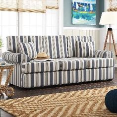 a blue and white striped couch sitting on top of a wooden floor next to a lamp