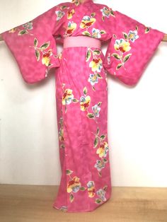 A 100% cotton Yukata Kimono Robe in bright pink & flowers. Sash sold separately. Fits a USA size L. MATERIAL:  100% Cotton.  Unlined, except for shoulder lining. PATTERN:  Bright flowers. COLOR:  Bright pink with bright floral print. CONDITION:  Used vintage.  Stained area on front sleeve top (see photo), otherwise great condition.   Belt NOT included. Kimono are Dry-clean only. My shop: https://kimonomemoirsjp.etsy.com. SIZE: Women's LARGE Kimono. (Model is 5'7" wearing 1.5" platform sandal) Wingspan- 53 inch (134.5 cm) across the top, sleeve end to sleeve end. Length- 63.5 inch (161.5 cm) from neckline to bottom of robe. Sleeve length- 18.75 inch (47.5 cm) from top to bottom of sleeve. Width- 24.5 inch (62 cm) measured arm-pit to arm-pit across the back. SHIPPING: **All international ord Fitted Pink Summer Kimono, Pink Floral Print Long Sleeve Kimono, Pink Long Sleeve Cotton Kimono, Long Sleeve Pink Cotton Kimono, Traditional Pink Summer Kimono, Traditional Pink Kimono For Spring, Pink Cotton Summer Kimono, Pink Cotton Kimono For Summer, Long Pink Printed Kimono