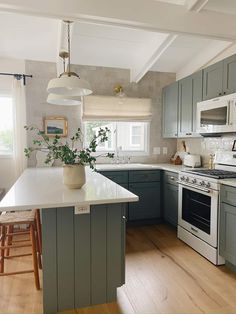 a kitchen with gray cabinets and an island in the middle is seen from across the room