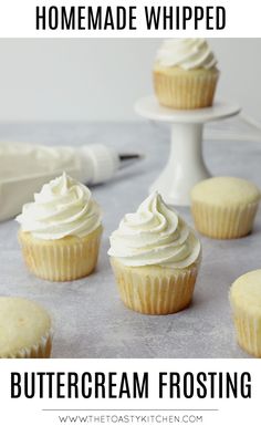 cupcakes with white frosting sitting on a table next to a cake server