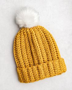 a yellow knitted hat with a white pom - pom on the top