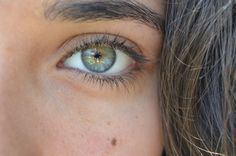 a woman's eye with long hair and green eyeshade, close up