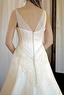 the back of a woman's wedding dress in front of a mirror