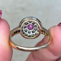 An antique gemstone ring featuring a 0.40 carat oval cut pink sapphire, bezel-set and surrounded by a double halo of old mine cut diamonds. Additional diamonds adorn the shoulders. The total diamond weight of this ring is 1.55 carats. This ring was handcrafted in silver on 14k yellow gold during the Victorian era, circa 1870. The measurements of this ring are approximately 12.21mm x 12.31mm. This ring can be resized to any finger size at no extra charge. If you have any questions about the Amien Antique Oval Sapphire Ring With Rose Cut Diamonds, Victorian Sapphire Ring With Diamond Oval Shape, Victorian Sapphire Ring With Oval Brilliant Cut, Victorian Oval Sapphire Ring With Diamond, Heirloom Oval Halo Ring With Bezel Setting, Oval Halo Ring With Rose Cut Diamonds For Promise, Oval Ruby Ring With Rose Cut Diamonds, Victorian Ruby Ring With Rose Cut Diamonds, Vintage Diamond Cluster Ring With Halo