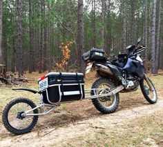 a motorcycle with a side car attached to it on a dirt road in the woods