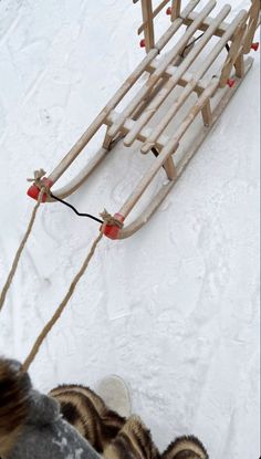 a dog pulling a sled with two people in it on the snow covered ground