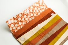 an orange and white flowered cloth is folded on top of another piece of fabric