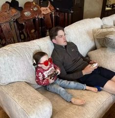 a man sitting on top of a couch next to a little boy