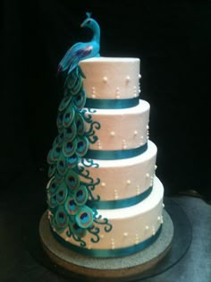 a three tiered cake with peacock decorations on it