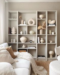 a living room filled with lots of white furniture and shelves full of different types of vases