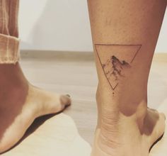 a person's foot with a mountain tattoo on the side of their left leg