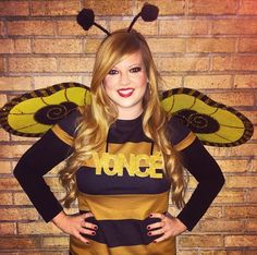 a woman wearing a bee costume standing in front of a brick wall with her hands on her hips