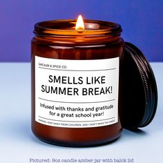 a candle that is sitting next to a blue background with the words smells like summer break on it