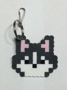 a black and white cat keychain with pink eyes on it's face