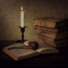 an open book with a candle on it next to a judge's gavel