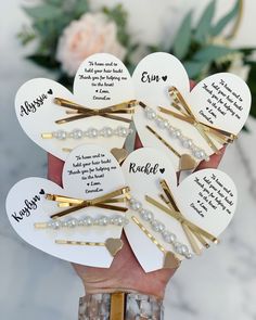 a person holding several heart shaped brooches in their hand with names on them