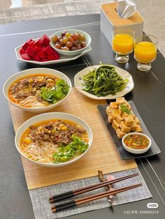 a table topped with plates of food and bowls of soup next to glasses of orange juice