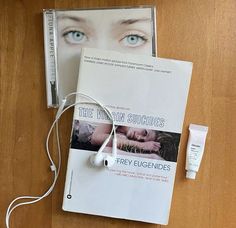 a book, earbuds and eye cream are on the floor