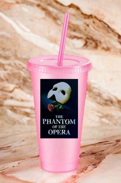 a plastic cup with a pink lid and straw in front of a marble background that says, the phaeom of the opera