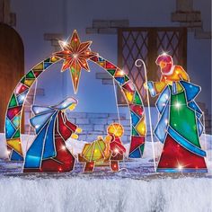 three colorful glass figurines sitting on top of a white table covered in snow